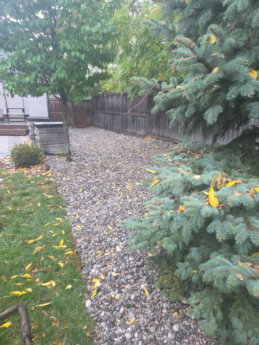Small stone installation along fence in backyard
